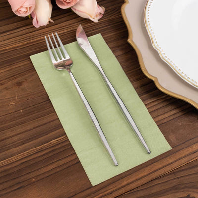 Silver fork and knife on a green napkin, styled for a dining table setting.