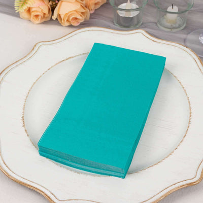 Turquoise napkins stacked on a decorative plate.