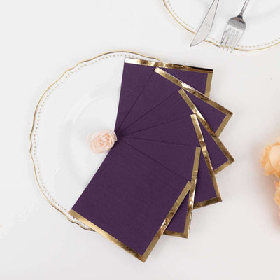 Purple invitations with gold foil edges on a decorative plate.