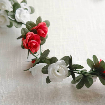 Artificial flower crown with red and white roses and green leaves.
