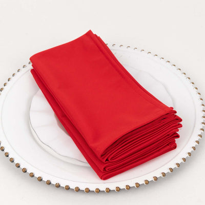 Red napkins neatly stacked on a decorative plate