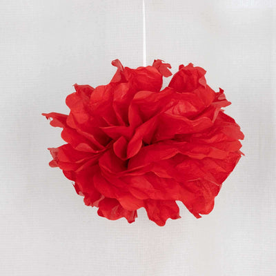 Red tissue paper pom pom decoration hanging on a string.