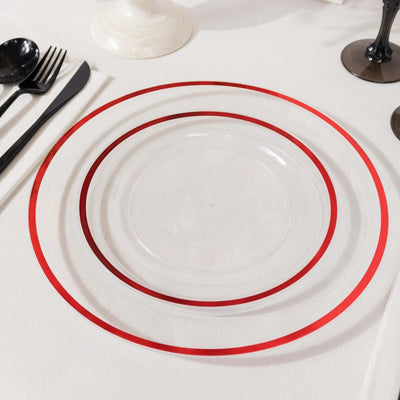 Clear plates with red rims on a table setting.