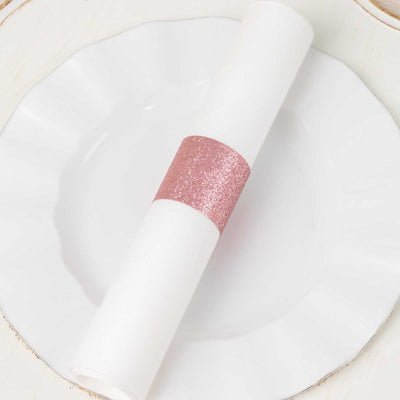 White napkin roll with pink glitter band on a decorative plate.