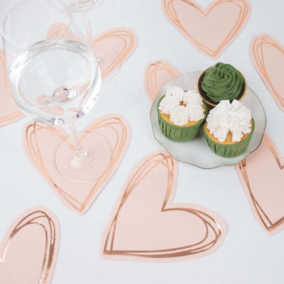Heart-shaped coasters with cupcakes and a glass of water on a table.