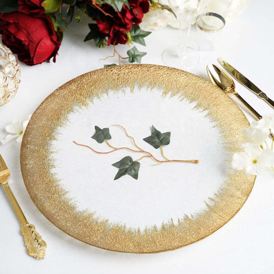 Elegant gold-rimmed plate with greenery on a white table setting.