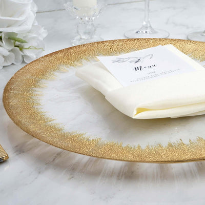 Elegant gold-rimmed plate with a napkin and menu card on a marble table.