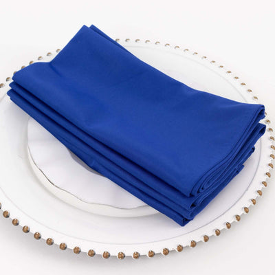 Blue table napkins neatly folded on a decorative plate.