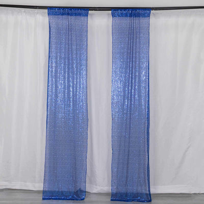 Blue sequin curtain panels hanging on a rod against a white backdrop.