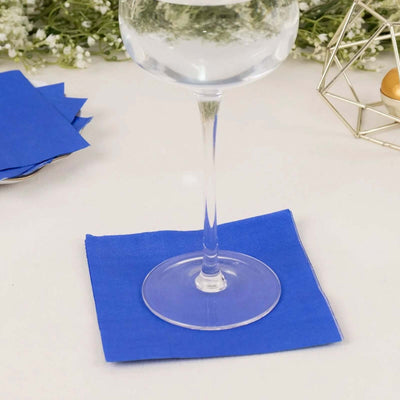 Clear glass with water on a blue napkin, set against a light background.
