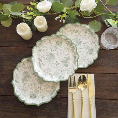 Elegant floral paper plates set on a rustic wooden table with cutlery and candles.