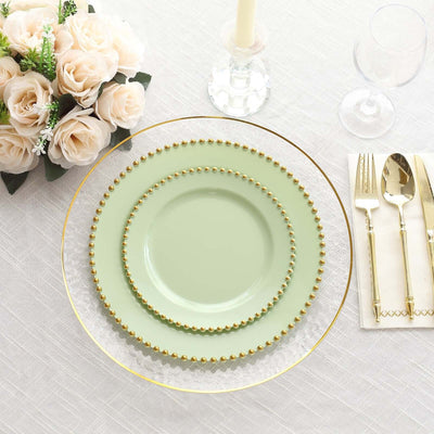 Elegant green and gold dinnerware set arranged on a table with floral centerpiece.