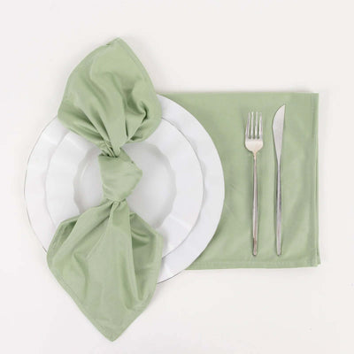 Green napkin elegantly tied on a white plate with silver cutlery on a placemat.