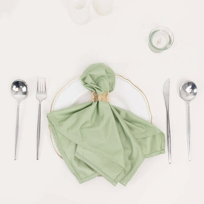 Green napkin elegantly arranged on a white plate with silver cutlery.