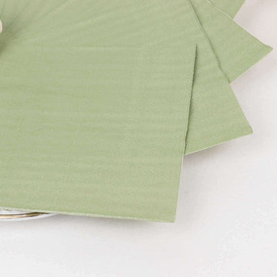 Green fabric napkins arranged neatly on a plate.