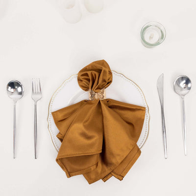 Elegant brown satin napkin tied with a decorative bow on a white plate.