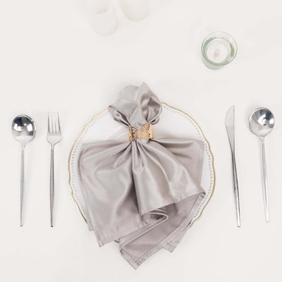 Elegant silver napkin with a decorative ring on a fine dining plate.