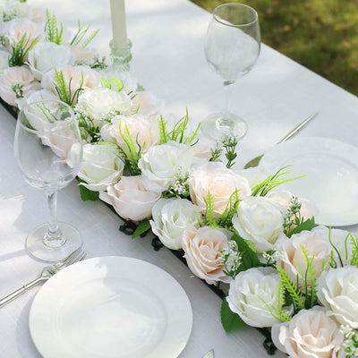 Elegant floral table centerpiece with white and pale pink roses and greenery.