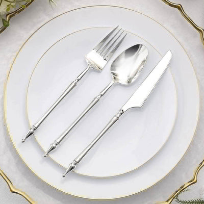 Elegant silver flatware set on a white plate with gold trim.
