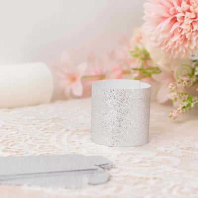 Silver glitter paper band on lace tablecloth with flowers in the background.