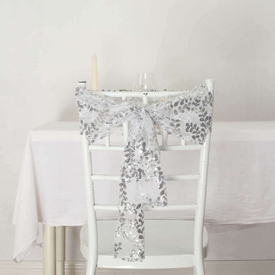 Silver sequin lace chair sash tied on a white chair in a minimal setting.