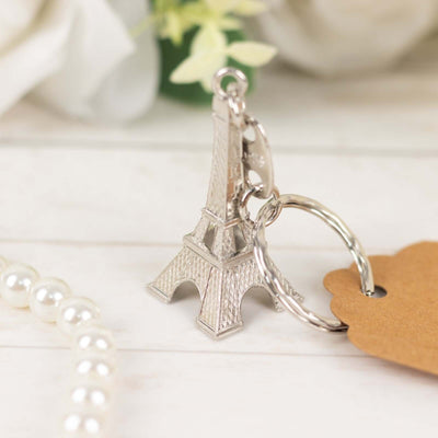 Eiffel Tower keychain on a wooden surface with pearls and tag.