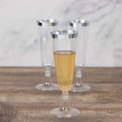 Set of elegant clear plastic champagne flutes with silver rims.