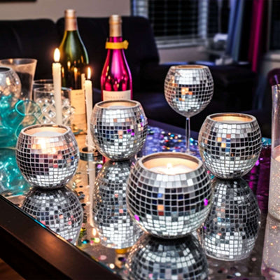 Disco ball candle holders on a festive table setting with drinks and decorative lights.