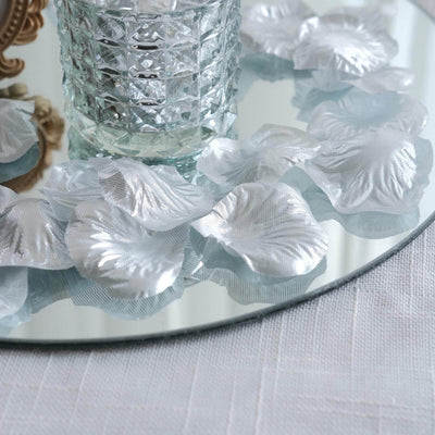 Silk flower petals on a mirrored surface with a decorative glass vase.