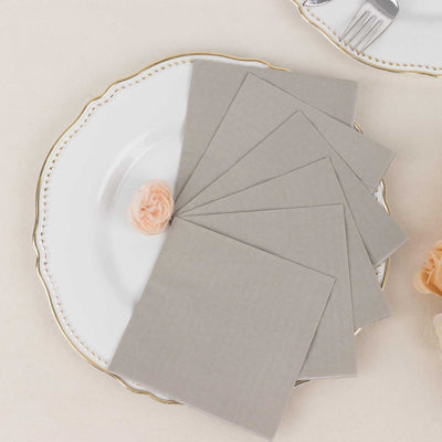 Gray linen napkins arranged on a decorative plate with a rose accent.
