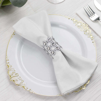 Elegant white napkin with decorative ring on a decorative plate.