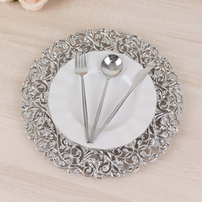Elegant silver decorative plate with cutlery arranged on a light wooden surface.
