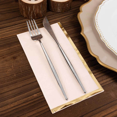 Silver fork and knife on a pink napkin with gold trim, styled on a wooden table.
