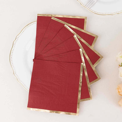 Red napkins with gold trim arranged on a white plate.