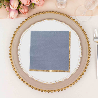 Elegant blue napkin with gold trim on a decorative plate, set for a formal dining experience.
