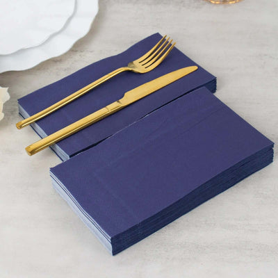 Navy blue napkins stacked with gold cutlery on a table