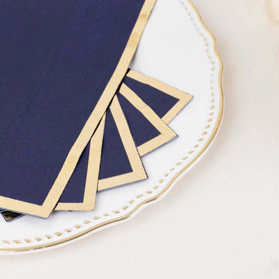Navy blue napkins with gold trim on an elegant white plate.