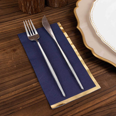 Elegant silver cutlery on a navy napkin with gold trim