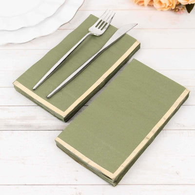 Green paper napkins with cream trim and silver cutlery on a wooden table.