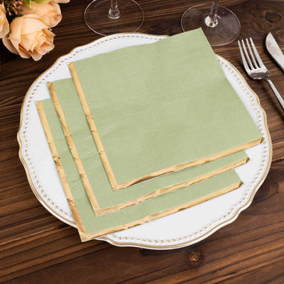 Green napkins with gold edges stacked on an elegant white plate.