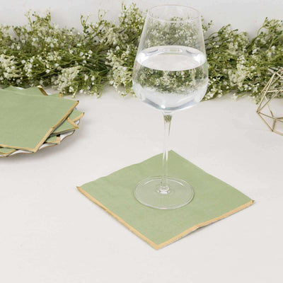 Green paper coasters with gold edges under a glass of water.