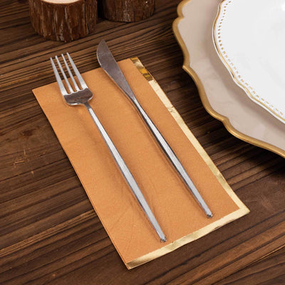 Silver fork and knife on a brown napkin with elegant tableware in the background.