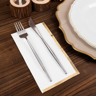 Silver fork and knife on a napkin with elegant tableware in the background.