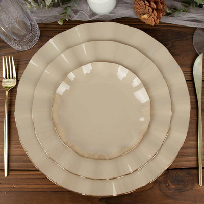 Elegant beige dinnerware set with gold trim on rustic wooden table.