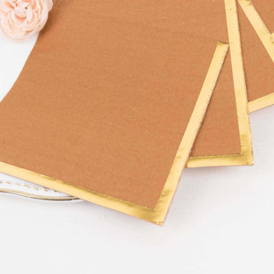 Brown paper napkins with gold trim on a white surface.
