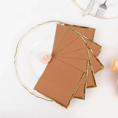 Elegant brown invitations with gold foil edges on a decorative plate.