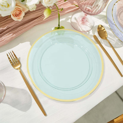 Aqua glass plate with gold rim on a dining table setting.