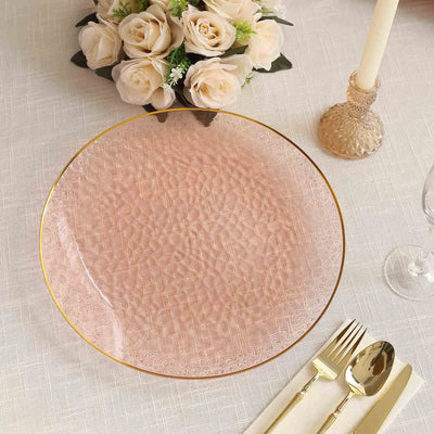 Elegant pink glass plate with gold rim on a table setting.