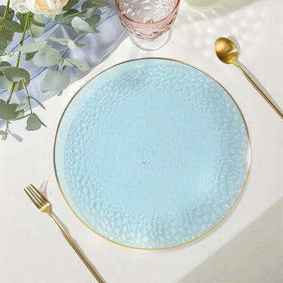Elegant blue textured glass plate with gold trim on a dining table setting.