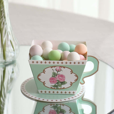 Mint green teacup filled with colorful decorative balls on a reflective surface.